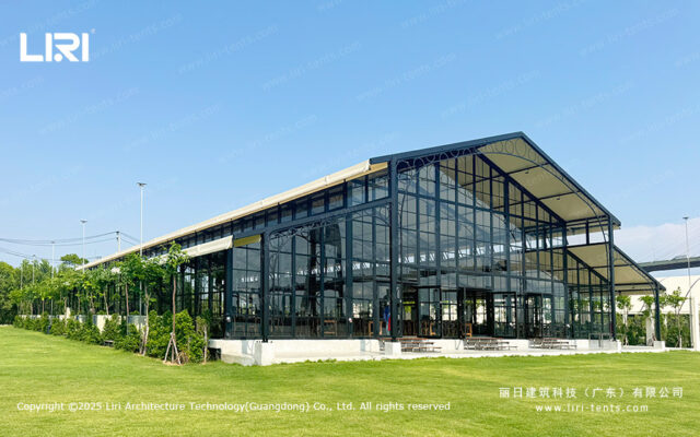Tenda tipo orangerie com exterior transparente, num relvado, com paredes de vidro