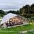 Exterior de um evento num jardim com tenda tipo orangerie, com paredes de vidro e iluminação noturna