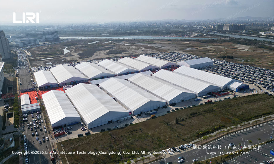 Vista aérea de um grande complexo de tendas de exposição com estrutura de alumínio, onde se realiza uma exposição mundial